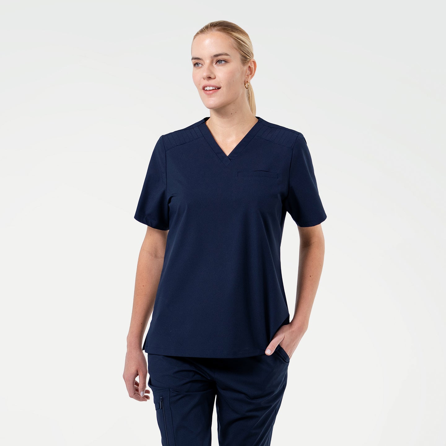 Image of A Female model wearing Eco Navy ZenFlex scrub top with matching scrub pants.
